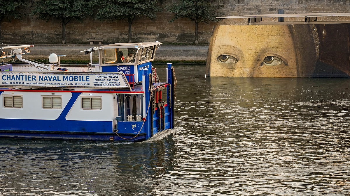 (AP Photo/ Dar Yasin) : A ship sails past reproductions of artworks decorating the banks of the River Seineat the 2024 Summer Olympics, Tuesday, July 30, 2024, in Paris, France. The men's Olympic triathlon has been postponed over concerns about water quality in Paris' Seine River, where the swimming portion of the race was supposed to take place. 